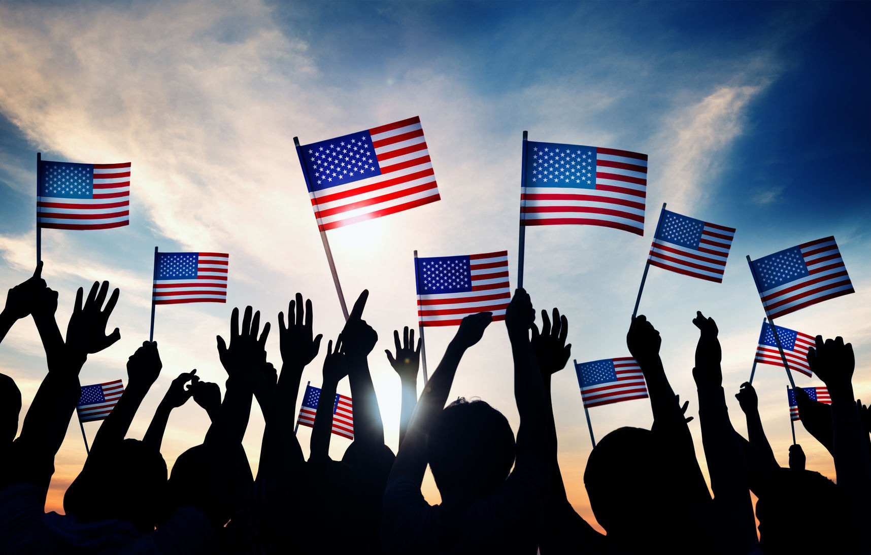 35336814 – group of people waving american flags in back lit
